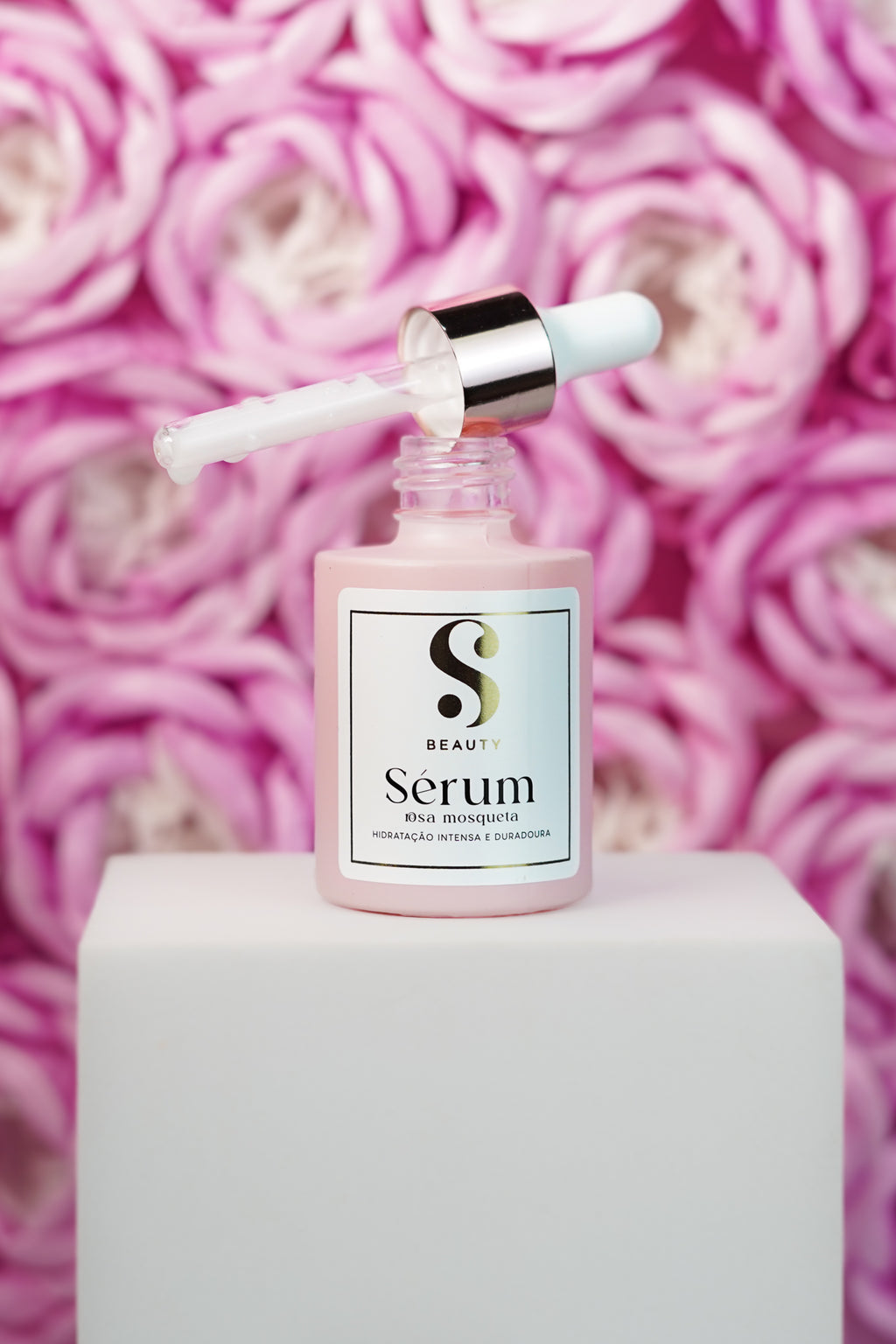 Sérum Rosa Mosqueta SBeauty · frasco com dropper sobre rosas naturais