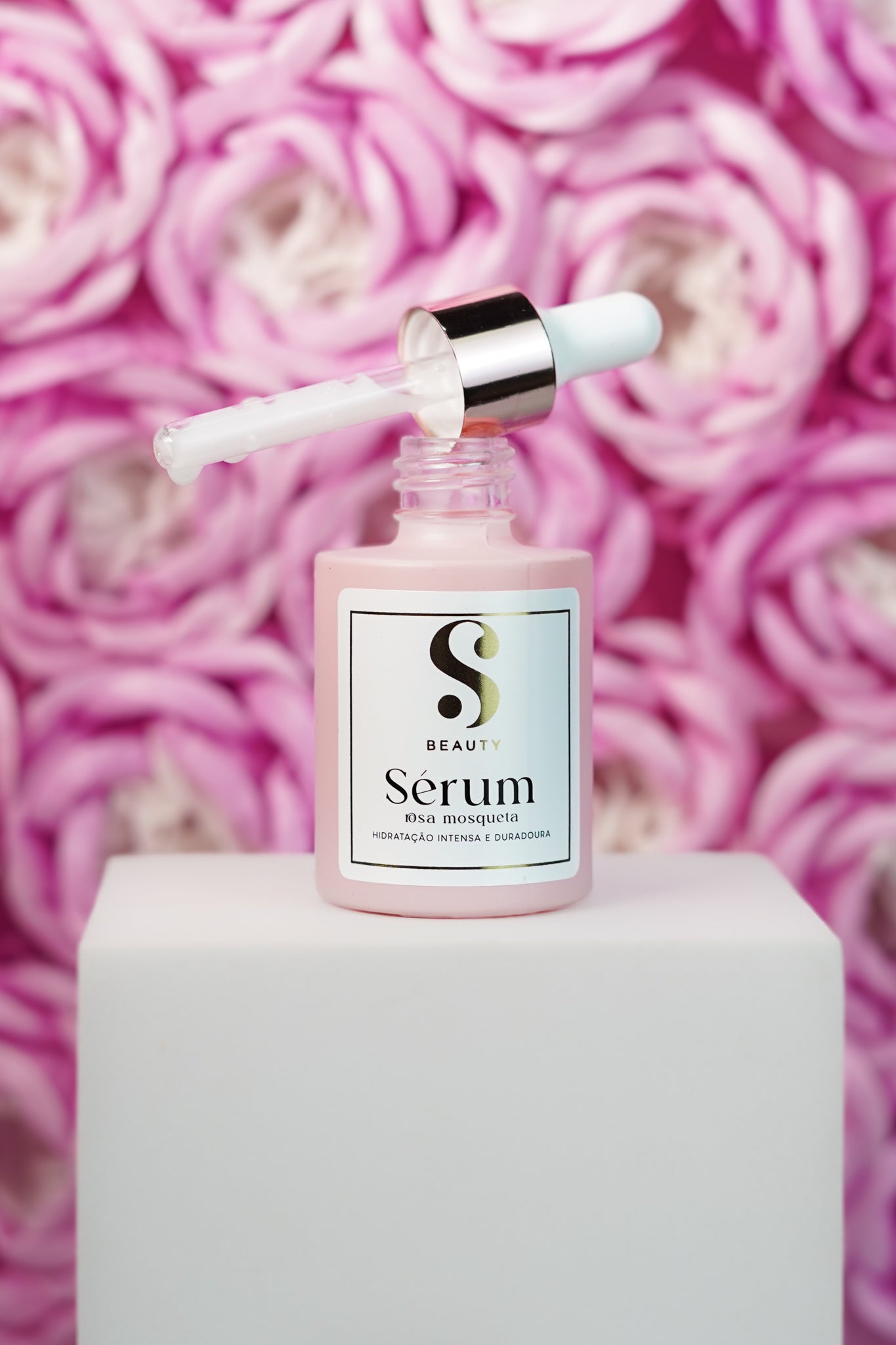Sérum Rosa Mosqueta SBeauty · frasco com dropper sobre rosas naturais